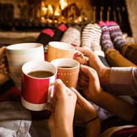 People raising their cups together in front of a fireplace